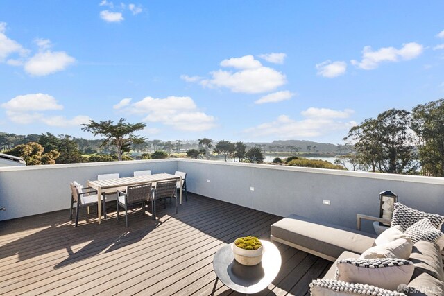 wooden terrace with outdoor dining space and a water view