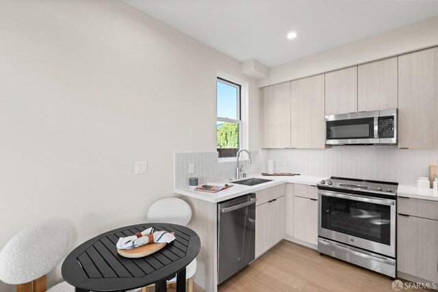 kitchen with stainless steel appliances, a sink, backsplash, modern cabinets, and light countertops