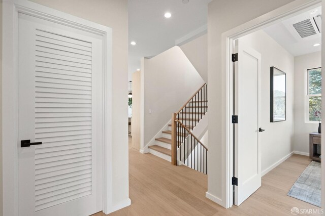 hallway with light wood-style flooring, baseboards, recessed lighting, and stairway