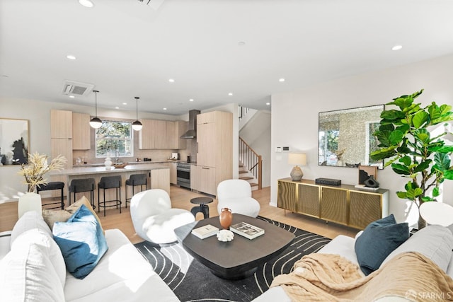 living room featuring light wood-style flooring, stairway, and recessed lighting