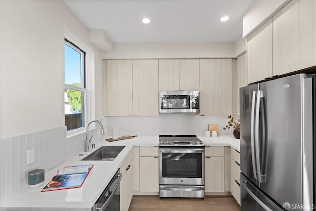 kitchen featuring stainless steel appliances, a sink, modern cabinets, light countertops, and recessed lighting