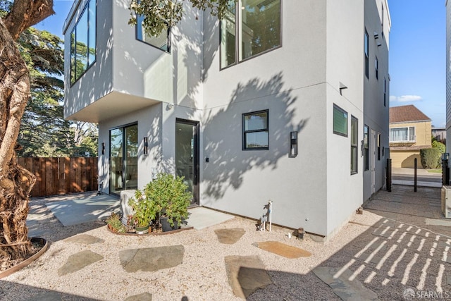 rear view of property featuring a patio, stucco siding, and fence