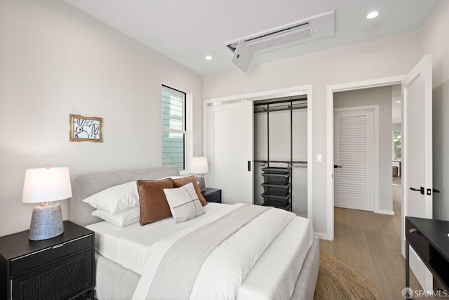 bedroom featuring wood finished floors, recessed lighting, a closet, and baseboards