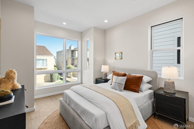 bedroom with wood finished floors, multiple windows, recessed lighting, and baseboards