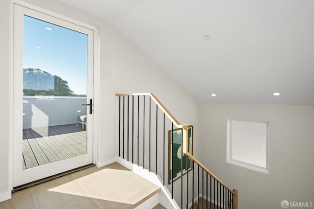 hall with an upstairs landing, recessed lighting, wood finished floors, and vaulted ceiling