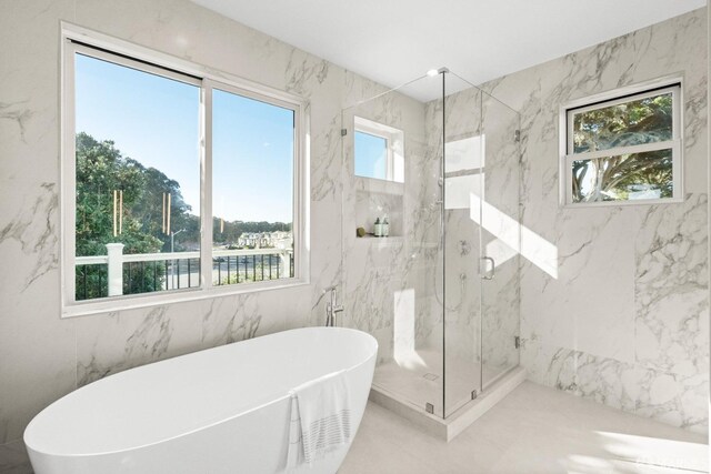 full bathroom with a marble finish shower and a freestanding tub