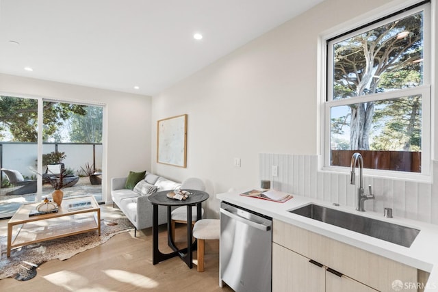 kitchen featuring stainless steel dishwasher, a sink, light wood-style floors, light countertops, and recessed lighting