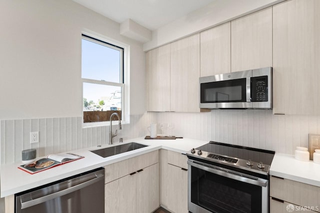 kitchen featuring appliances with stainless steel finishes, a sink, modern cabinets, light countertops, and tasteful backsplash