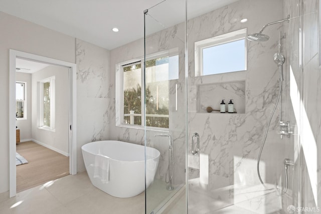 full bathroom featuring plenty of natural light, a marble finish shower, and a soaking tub