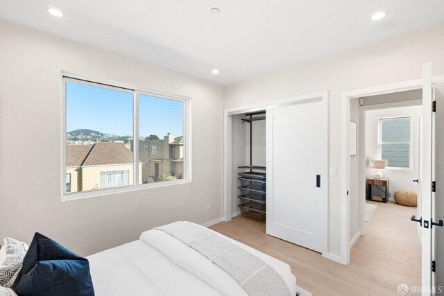 bedroom with light wood-style flooring, recessed lighting, baseboards, and a closet