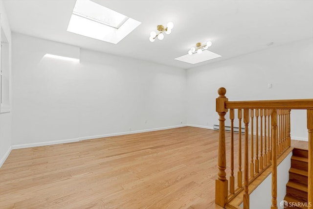 3870 18th St, San Francisco, CA 94114 - empty room featuring a skylight, a baseboard heating unit, light wood-style flooring, and baseboards