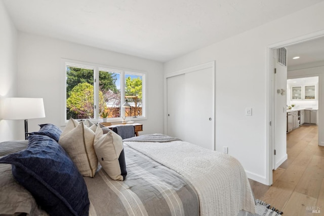 bedroom featuring a closet, baseboards, light wood-type flooring, and recessed lighting