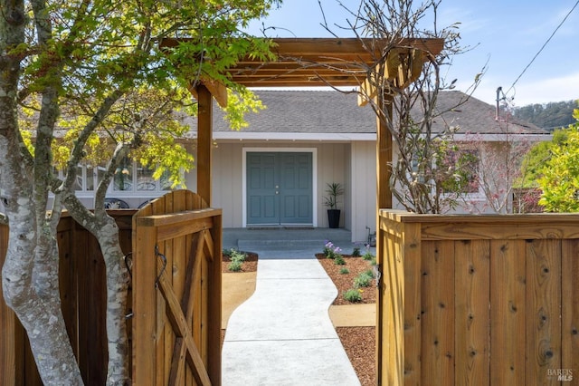 property entrance with fence, a gate, and roof with shingles