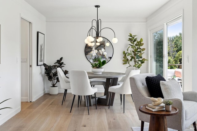 dining area featuring light wood-style flooring, an inviting chandelier, and baseboards
