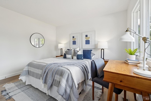 bedroom with wood finished floors, baseboards, and multiple windows