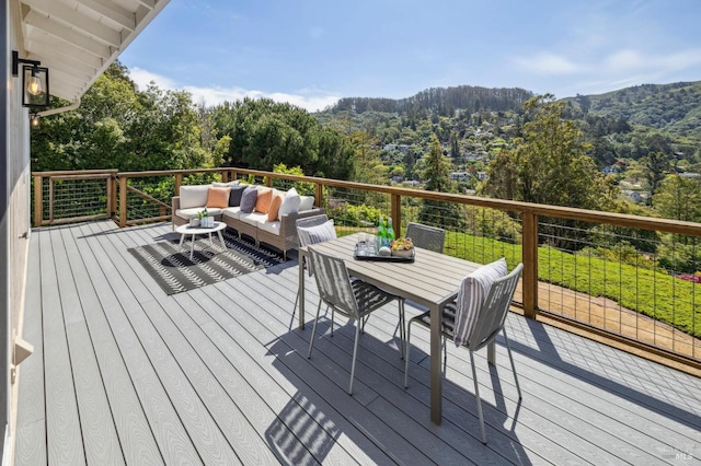 wooden terrace with a forest view, a mountain view, an outdoor living space, and outdoor dining area