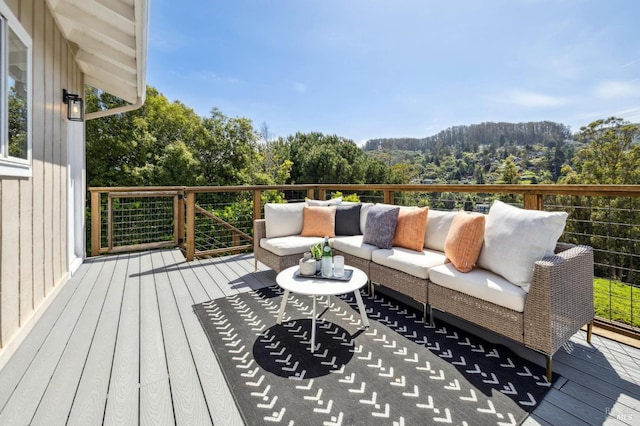 wooden deck with an outdoor living space and a view of trees