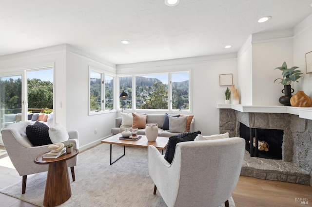 living room with a stone fireplace, a wealth of natural light, recessed lighting, and light wood-style floors