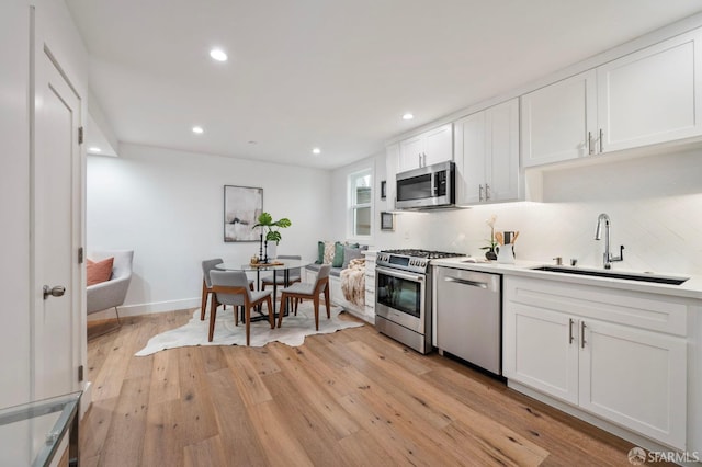 kitchen featuring white cabinetry, sink, stainless steel appliances, and light hardwood / wood-style floors