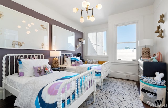 bedroom with an inviting chandelier, wood finished floors, and baseboards