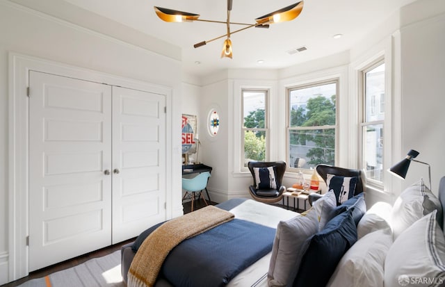 bedroom with wood finished floors, a closet, baseboards, a notable chandelier, and visible vents
