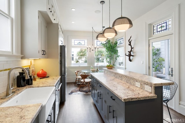 kitchen with tasteful backsplash, a sink, gray cabinets, dark wood-style flooring, and a kitchen island