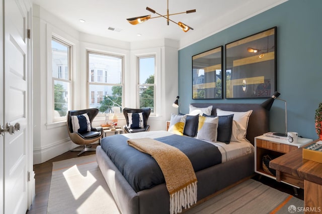 bedroom with a notable chandelier, wood finished floors, multiple windows, and visible vents