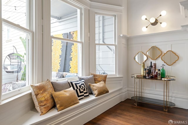 living area with a healthy amount of sunlight, dark wood-style floors, and a decorative wall