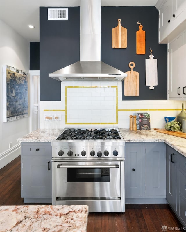 kitchen featuring wall chimney exhaust hood, high end stainless steel range oven, visible vents, decorative backsplash, and gray cabinets