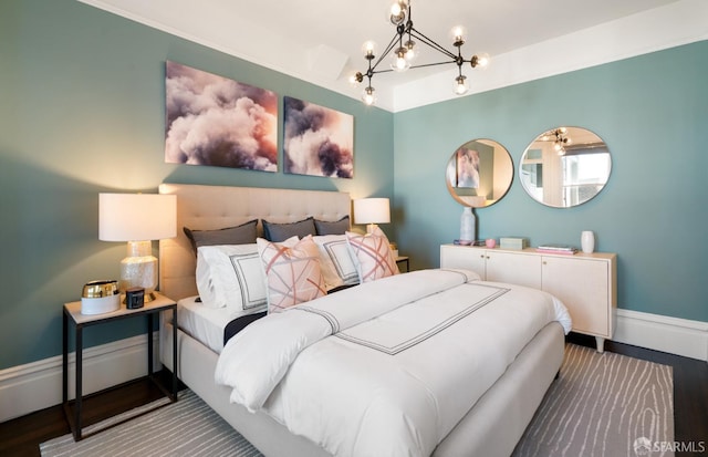bedroom featuring baseboards, wood finished floors, and a chandelier