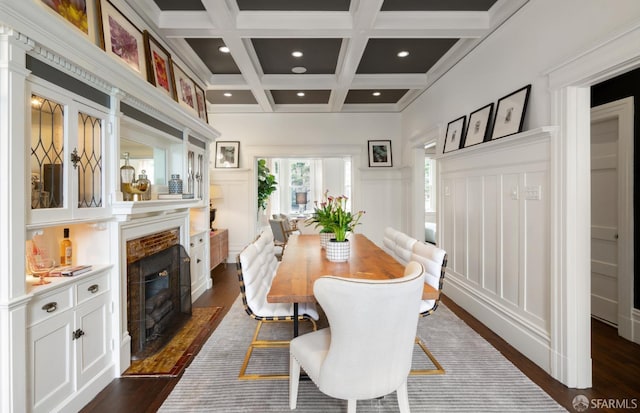 dining room with a fireplace with flush hearth, dark wood-style floors, coffered ceiling, beamed ceiling, and a decorative wall