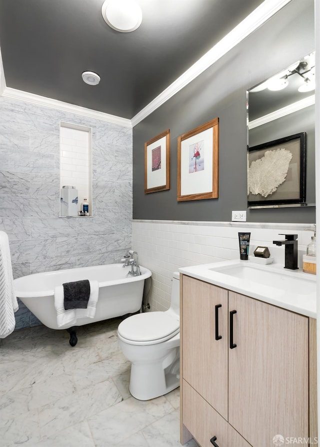 bathroom with a freestanding bath, toilet, vanity, tile walls, and crown molding