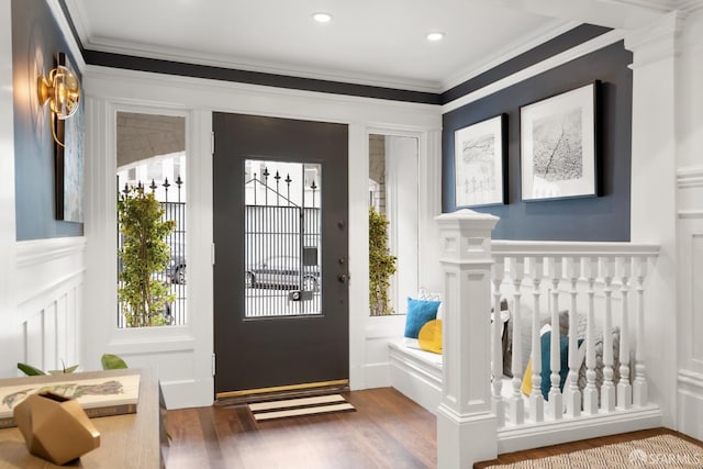 doorway with wood finished floors, a decorative wall, a wainscoted wall, and ornamental molding
