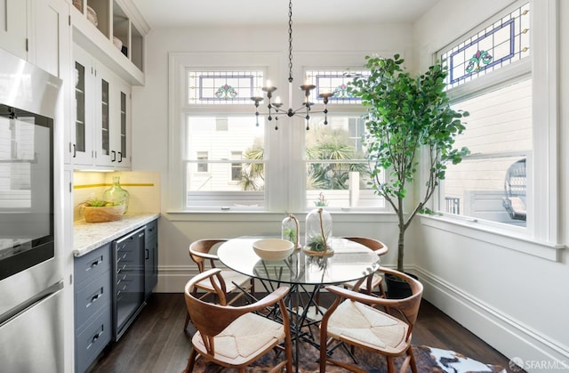 dining room with beverage cooler, baseboards, dark wood-style flooring, and an inviting chandelier