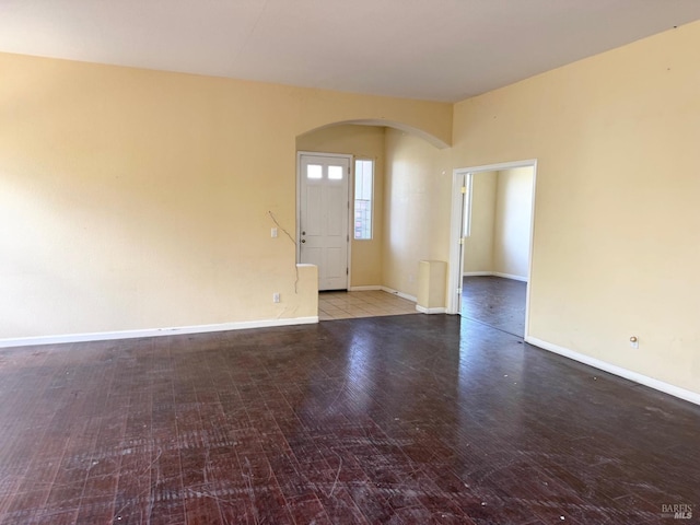 interior space with baseboards, arched walkways, and wood finished floors