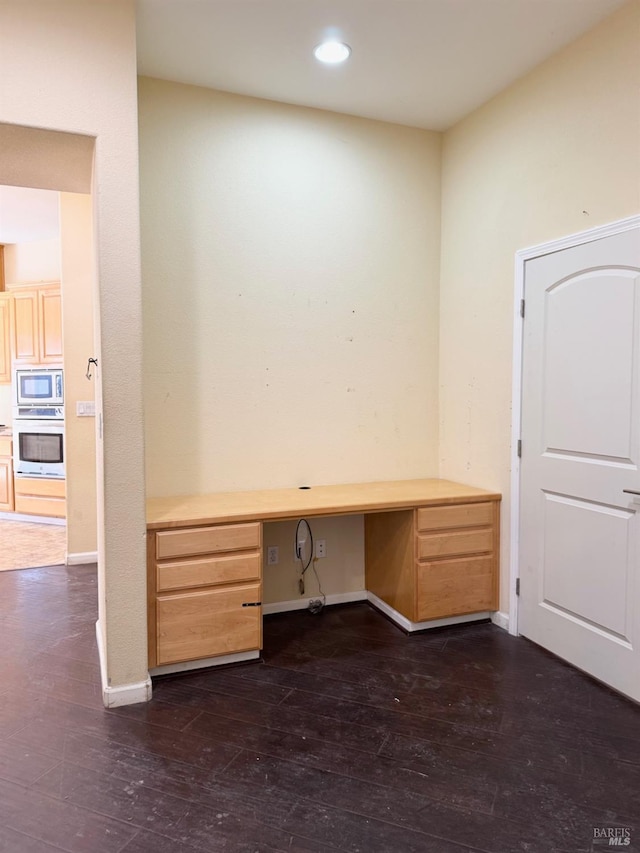 unfurnished office featuring baseboards, dark wood-style flooring, built in desk, and recessed lighting