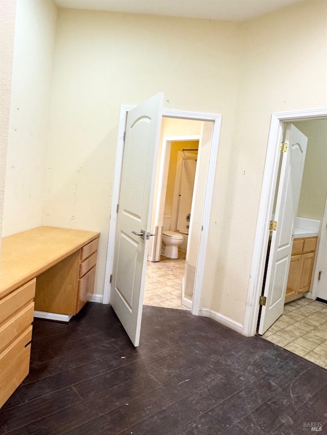 bathroom featuring wood-type flooring, baseboards, and toilet