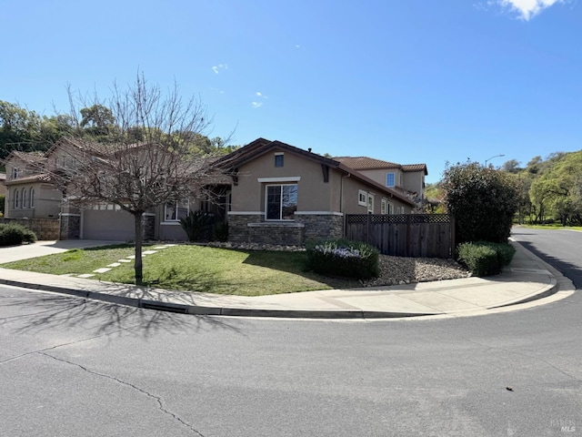 view of front of house with driveway, a garage, stone siding, fence, and stucco siding