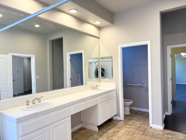 bathroom featuring double vanity, a sink, toilet, and baseboards