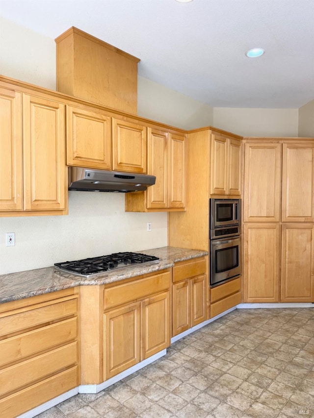 kitchen with stone countertops, light brown cabinets, under cabinet range hood, appliances with stainless steel finishes, and light floors