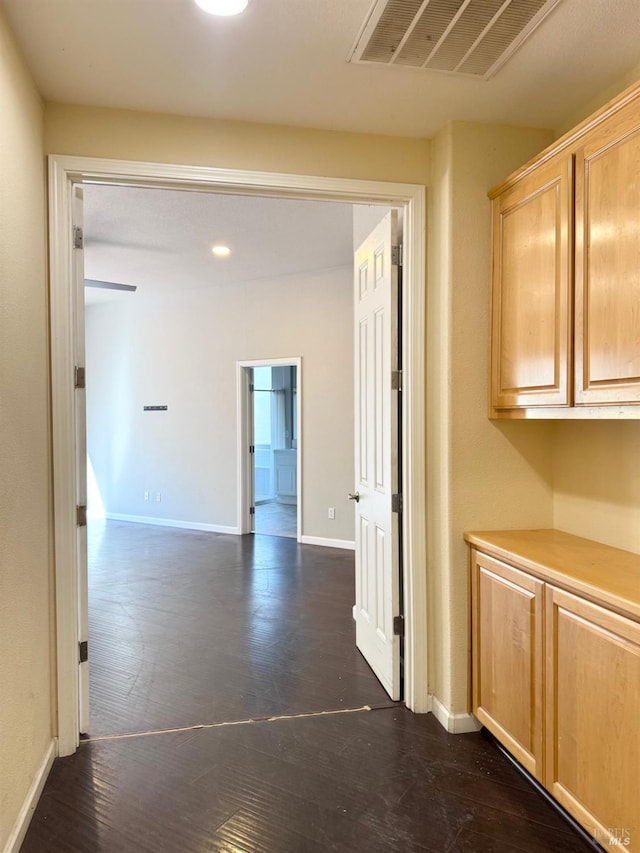 hallway with baseboards, visible vents, and dark wood finished floors