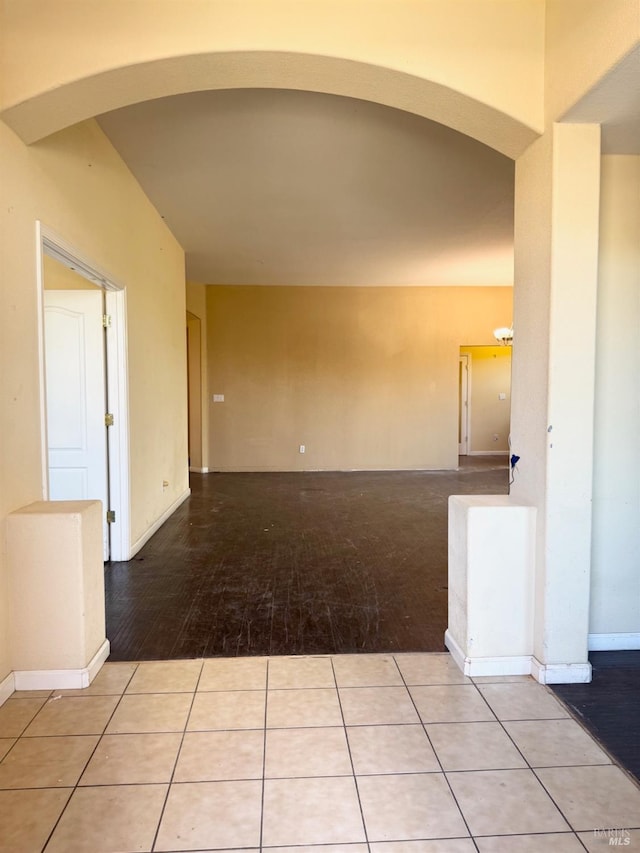 tiled empty room with arched walkways and baseboards