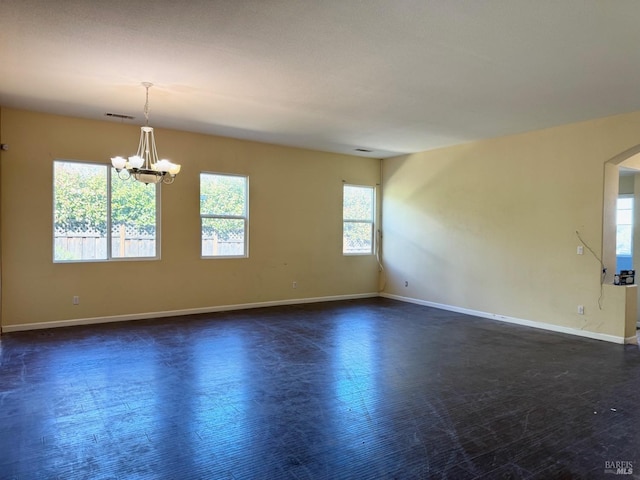 empty room with baseboards, dark wood-type flooring, arched walkways, and a notable chandelier