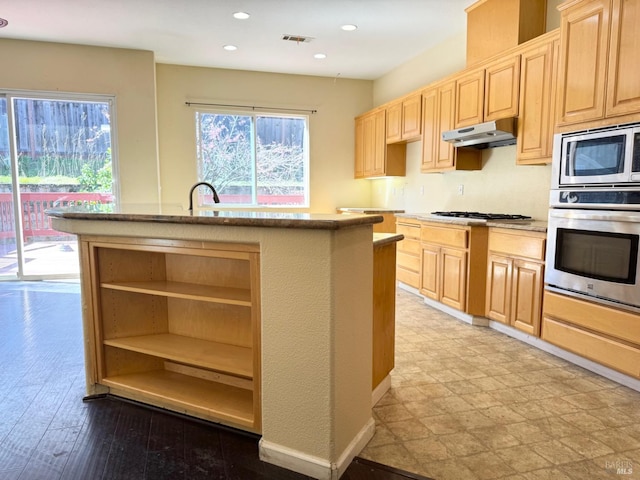 kitchen with under cabinet range hood, stainless steel appliances, a wealth of natural light, and light brown cabinetry