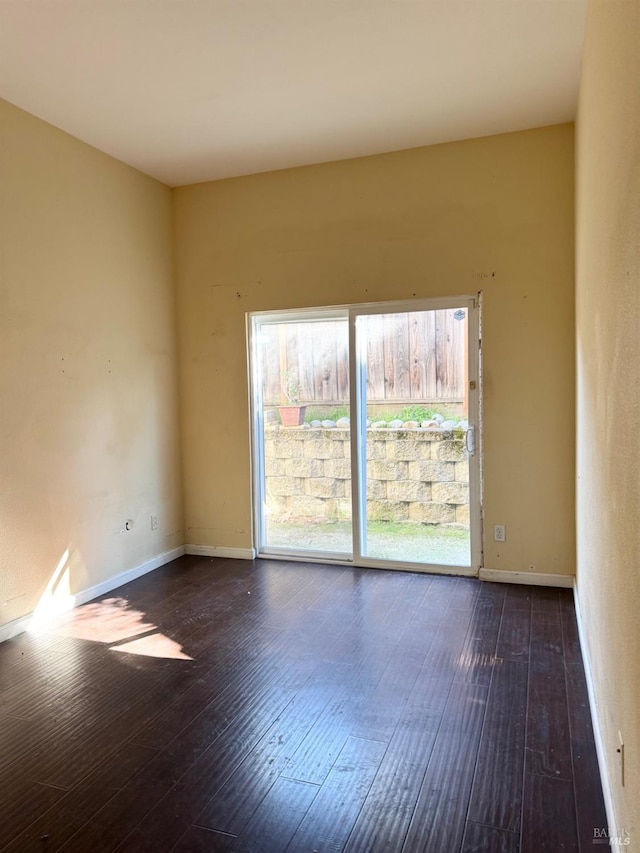 empty room with dark wood-style floors and baseboards