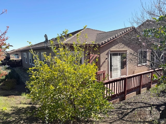 exterior space featuring a tiled roof, a wooden deck, and stucco siding