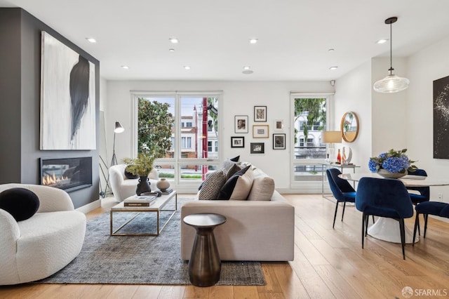 living room with a wealth of natural light, light hardwood / wood-style flooring, and a large fireplace