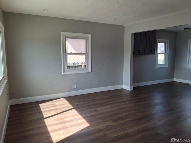 unfurnished room with baseboards and dark wood-style flooring