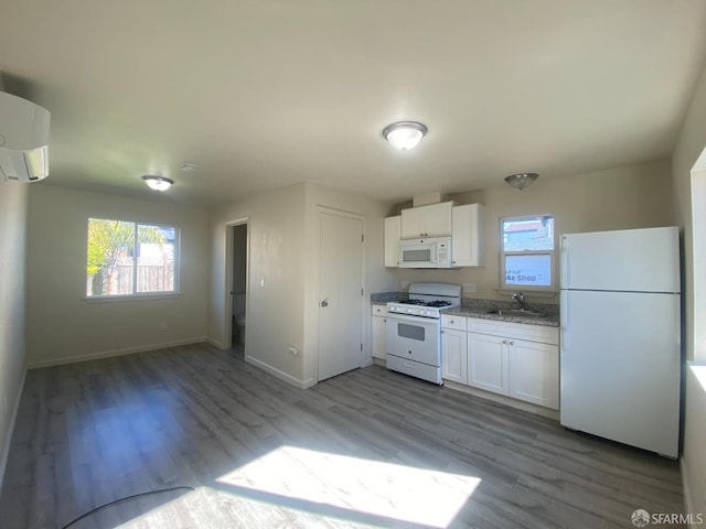 kitchen with white appliances, white cabinetry, a wall unit AC, and a sink