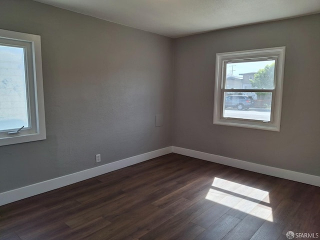 spare room featuring baseboards and dark wood-style floors